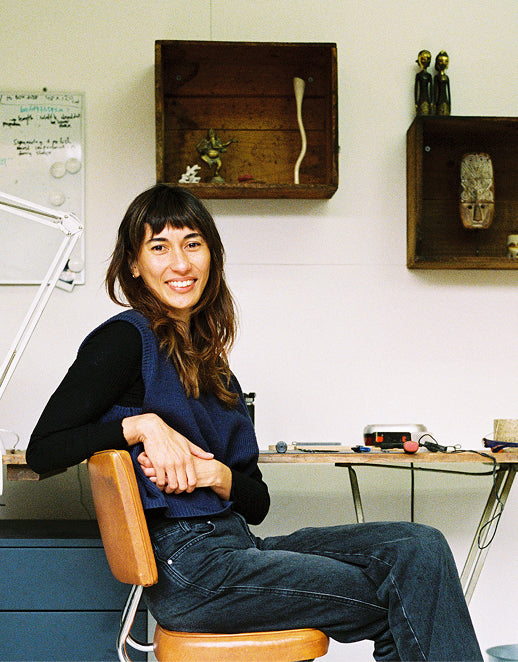 Jeweller Daphne Huguette sitting on a chair in her workshop