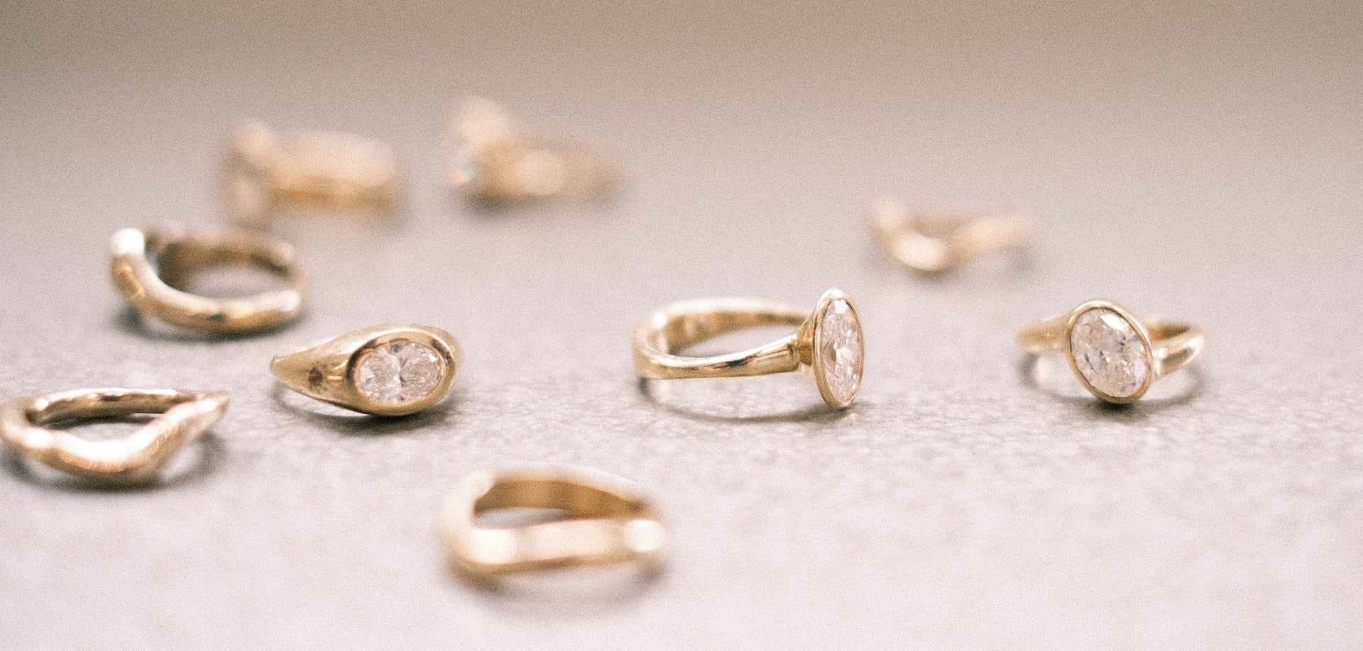 A collection of gold and diamond rings scattered on a textured surface