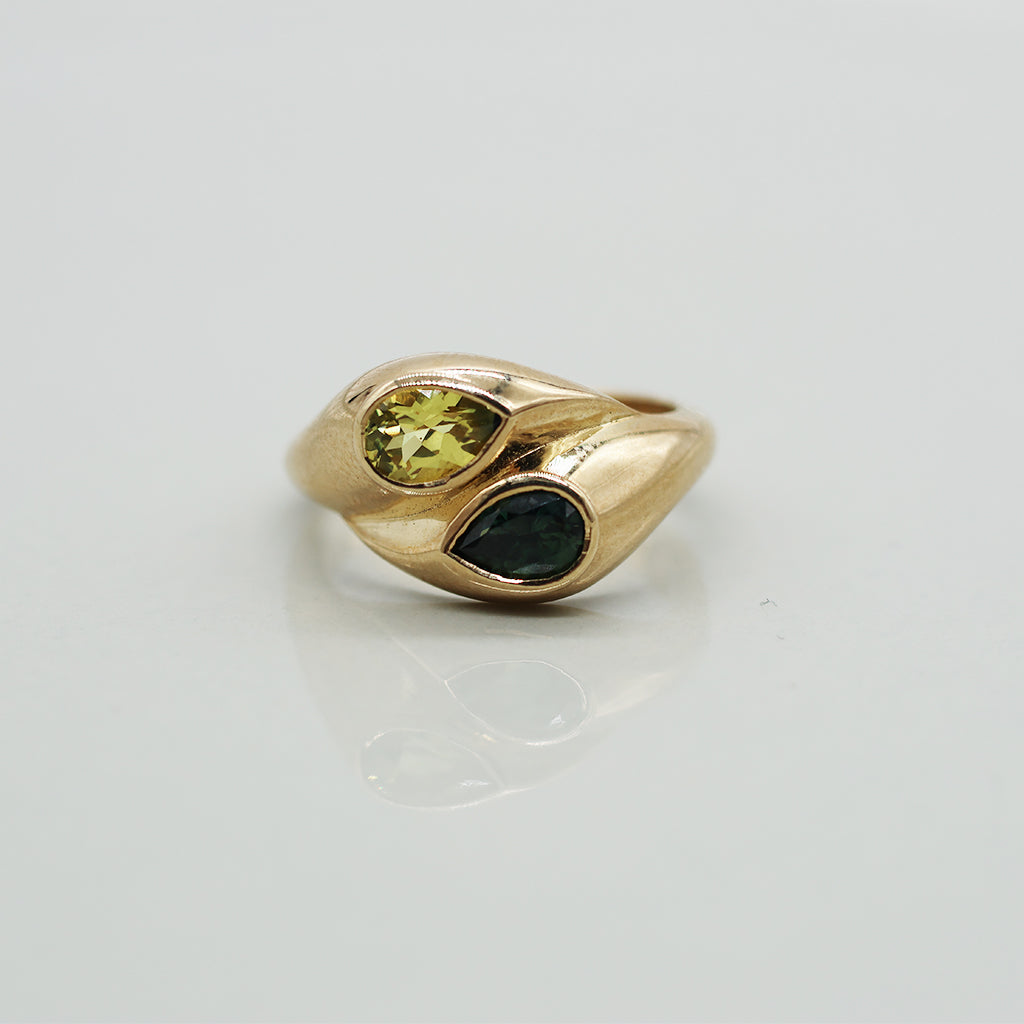 Gold ring with two gemstones on a light gray background