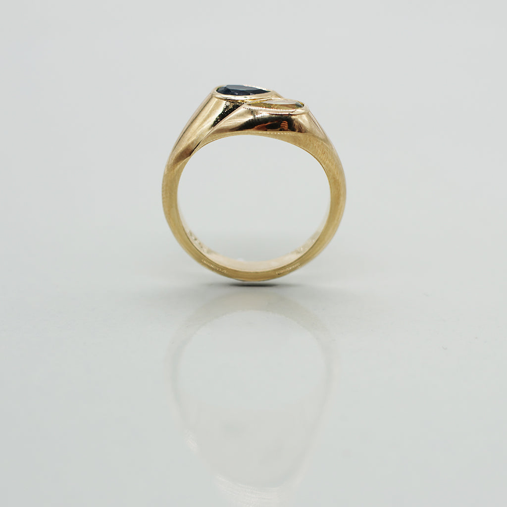Gold ring with a black gemstone on a light gray background