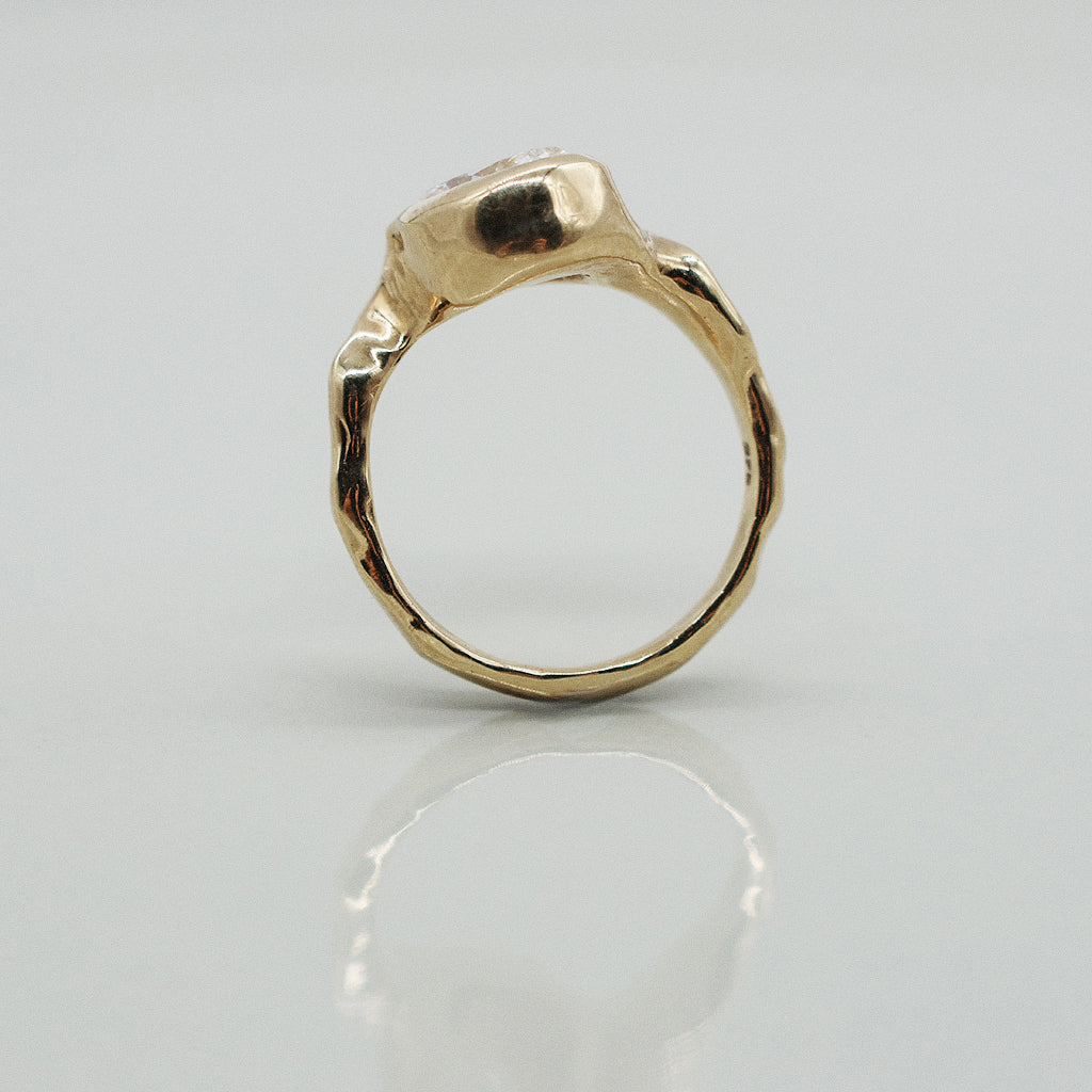 Gold ring with a textured band on a light gray background