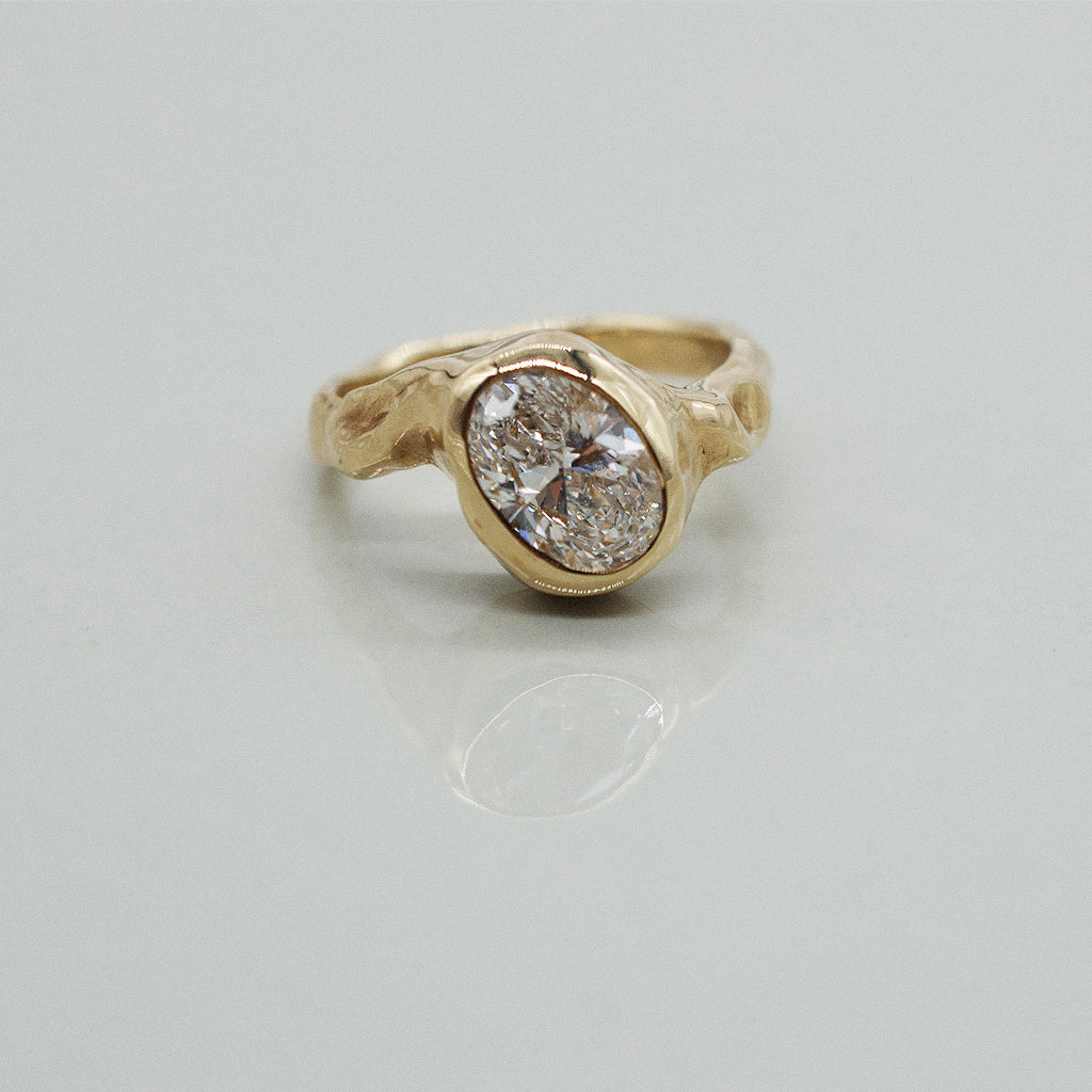 Gold textured ring with a diamond on a light gray background