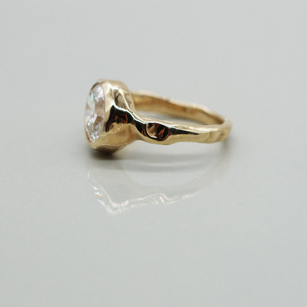 Gold ring with a diamond on a light gray background