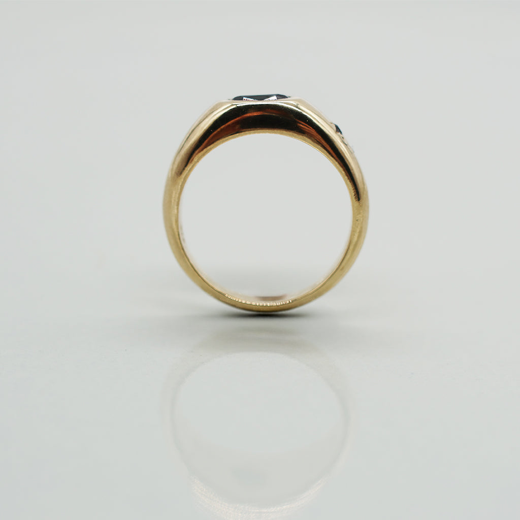Gold ring with a dark gemstone on a light gray background