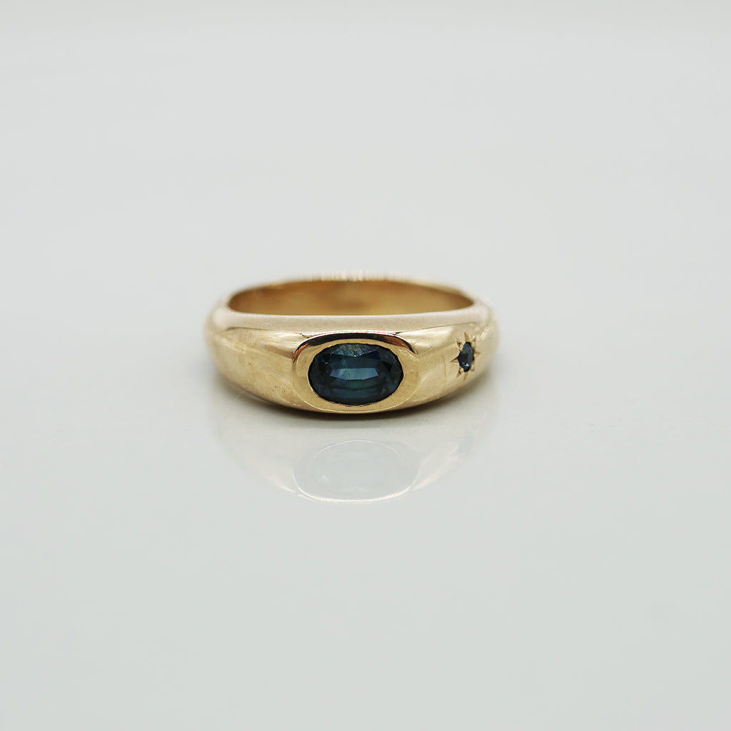 Gold ring with a blue gemstone on a light gray background