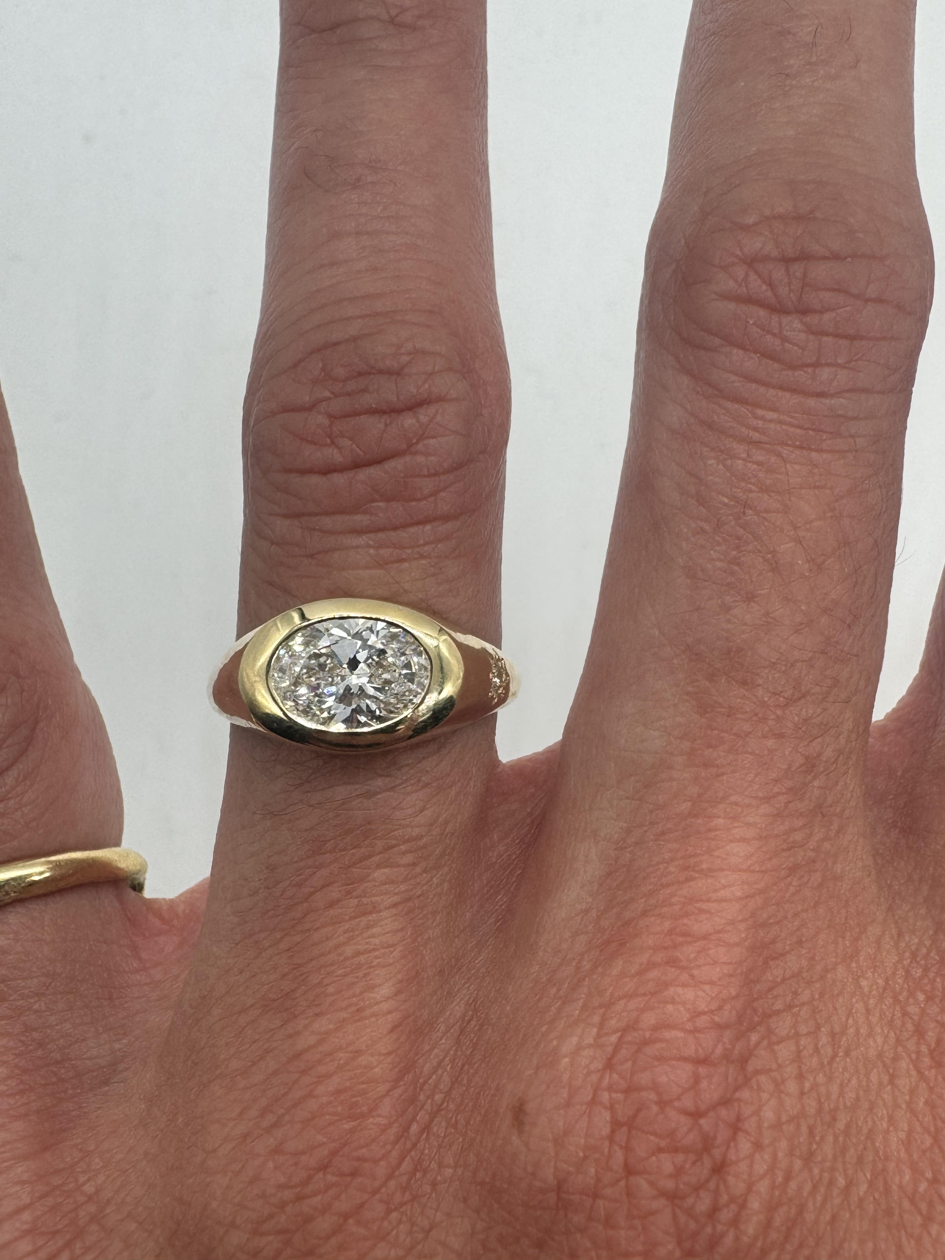 A gold ring with a large central diamond and a smaller sapphire on the side, set on a person's finger.