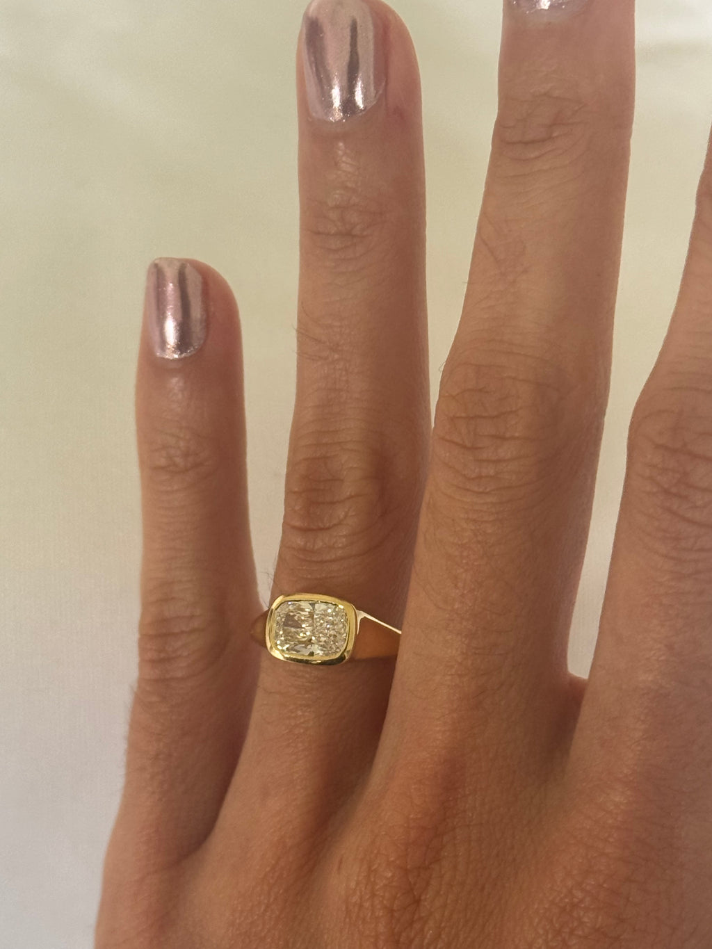 Gold ring on a person's finger with a plain background