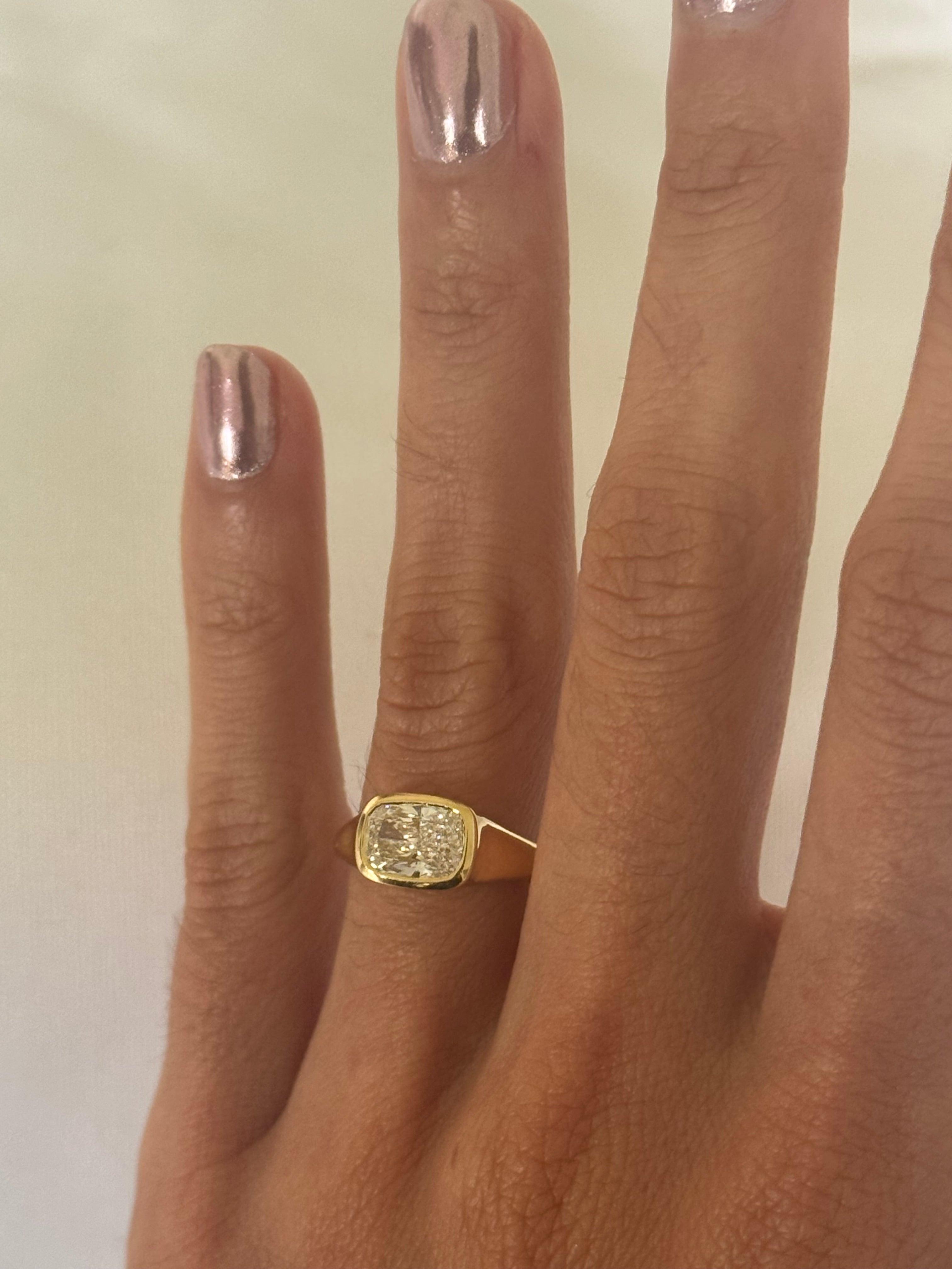 Gold ring on a person's finger with a plain background