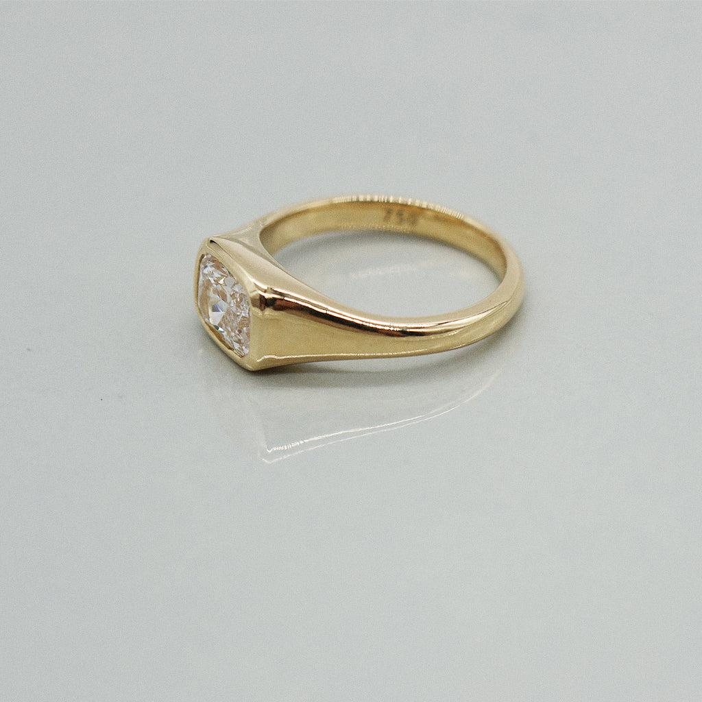 A yellow gold cushion ring featuring a large cushion brilliant-cut diamond center stone, set against a clean white background with a soft reflection.