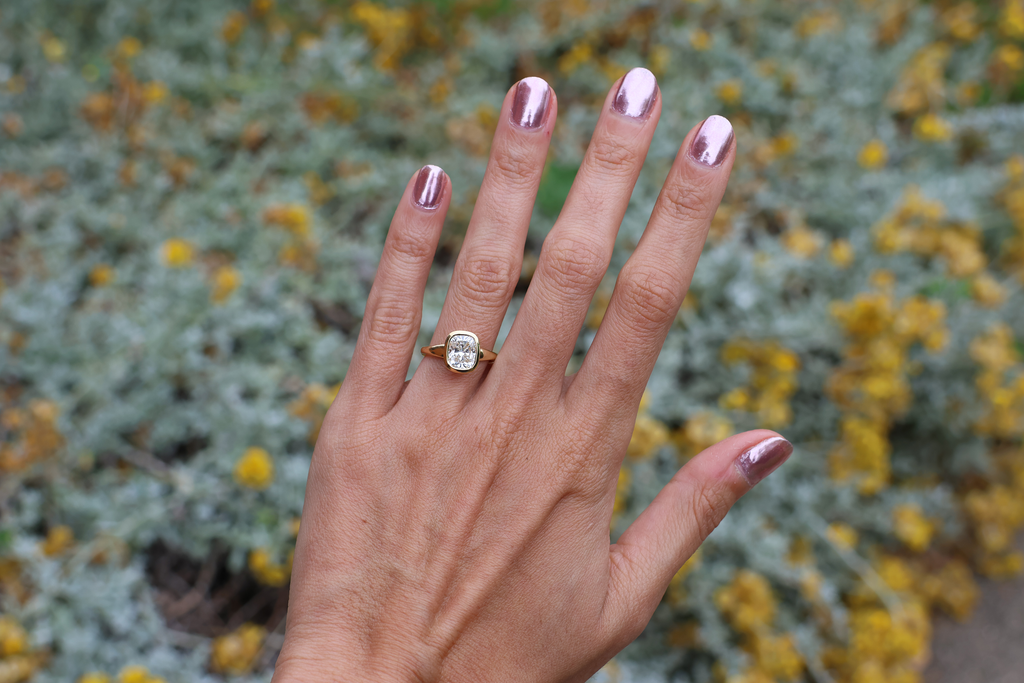 Hand with a ring on a blurred natural background
