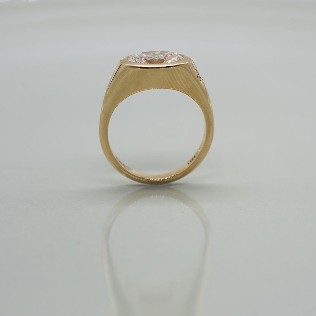 A yellow gold oval ring featuring a large oval brilliant-cut diamond centre stone set against a clean white background with a soft reflection.
