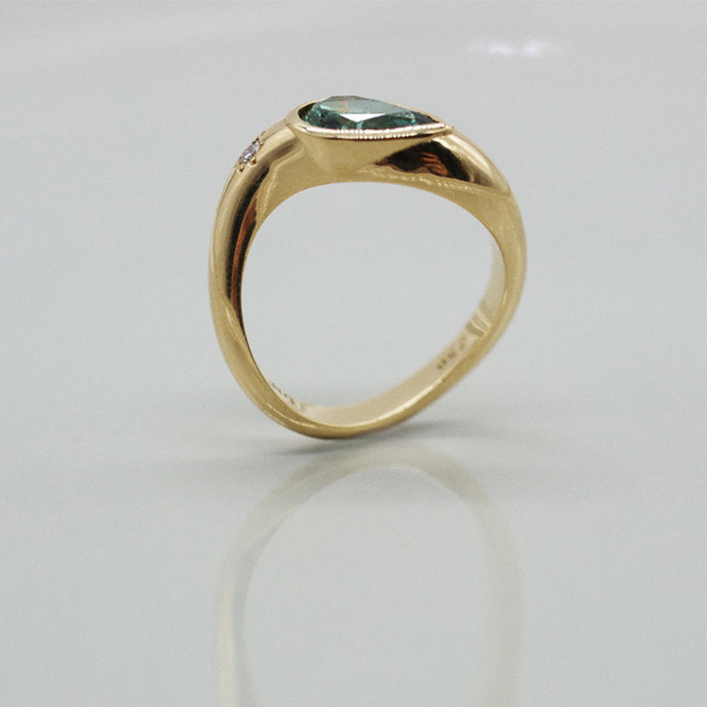 Gold ring with a blue gemstone on a light gray background