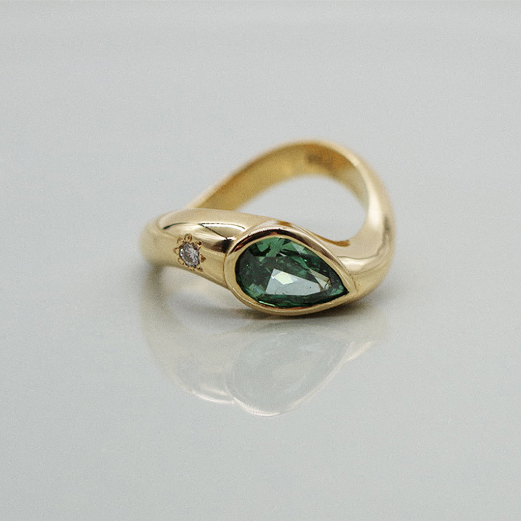 Gold ring with a green gemstone on a gray background