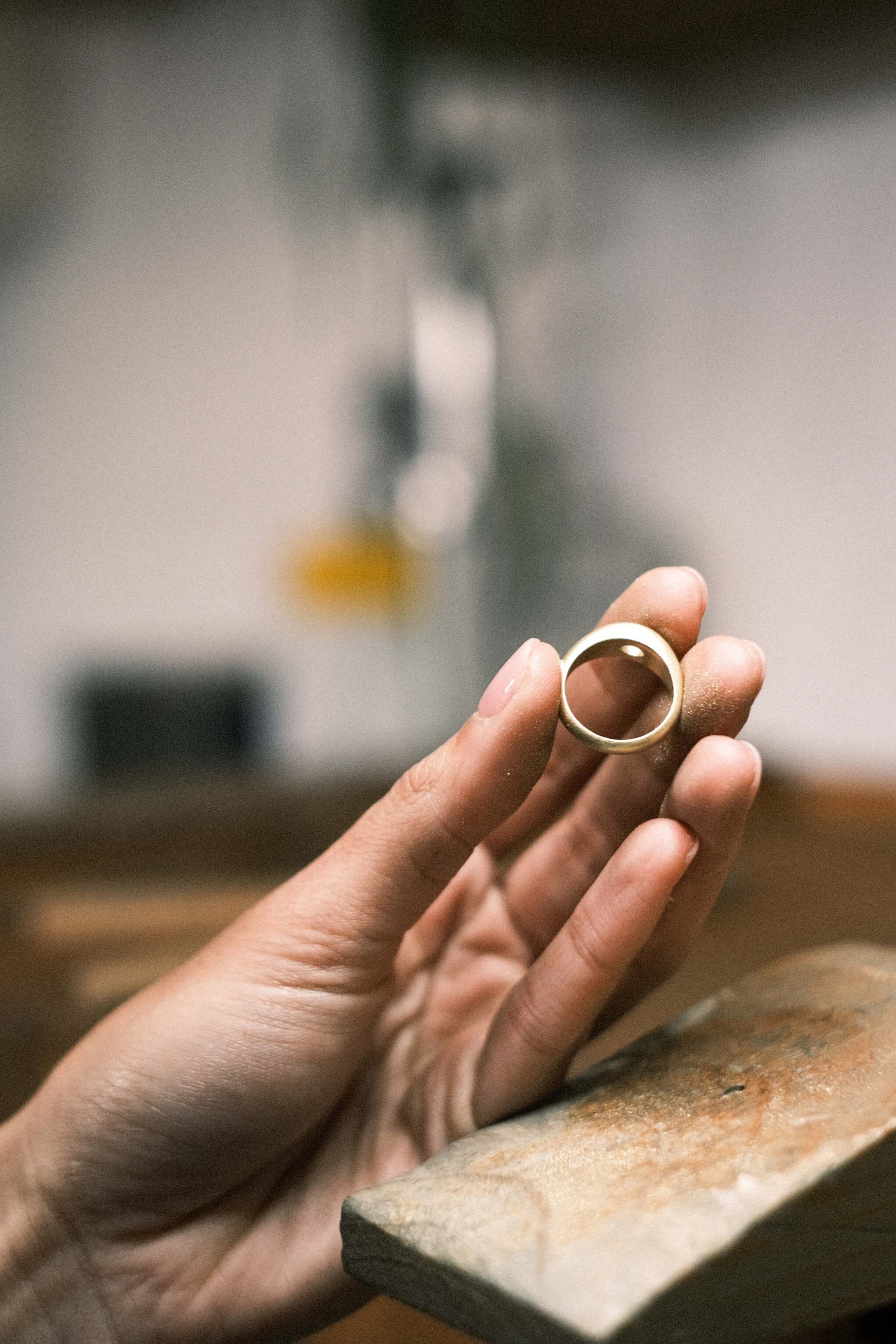 Hand holding a gold ring in the jewellers workshop