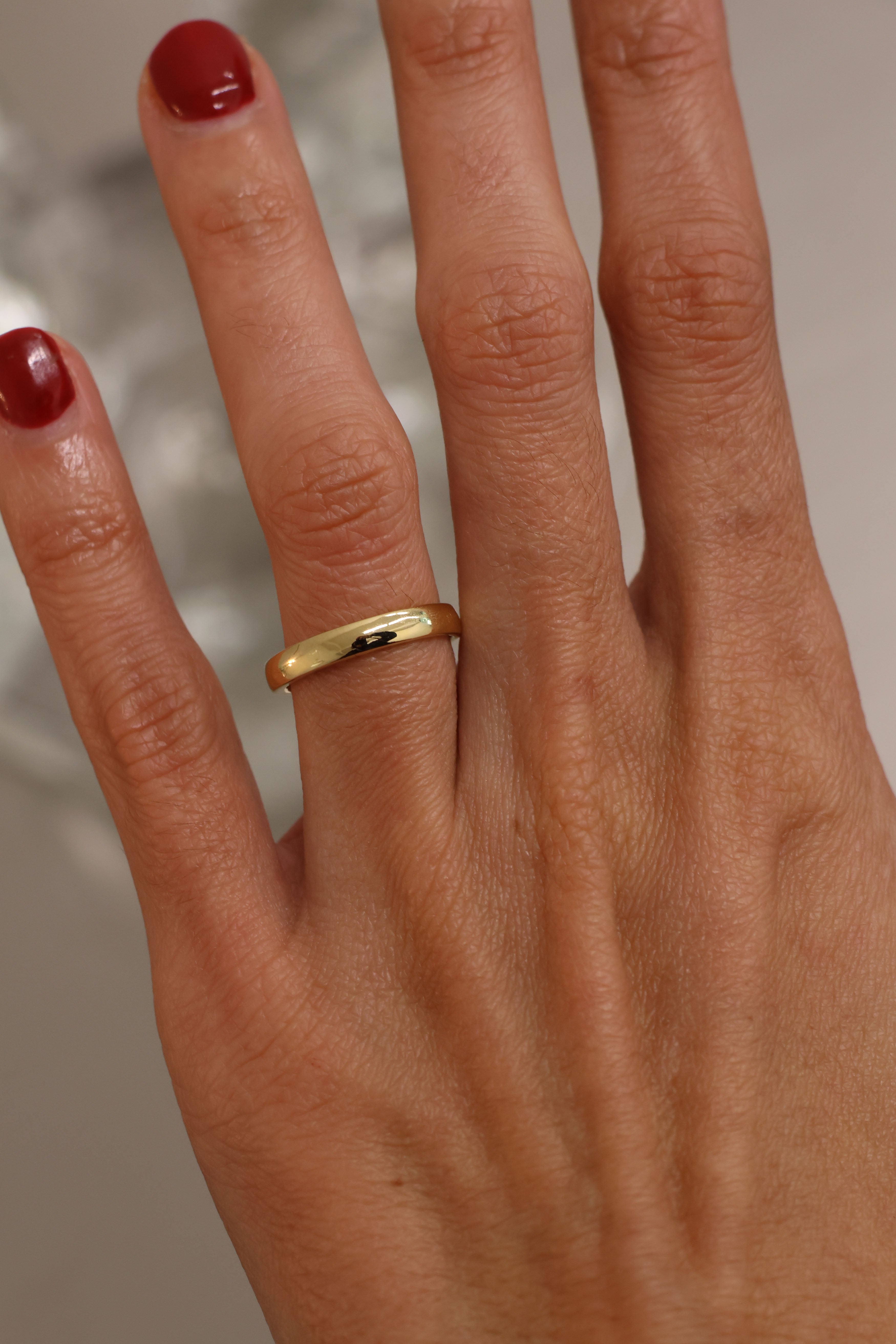 Hand wearing a gold ring with a blurred background