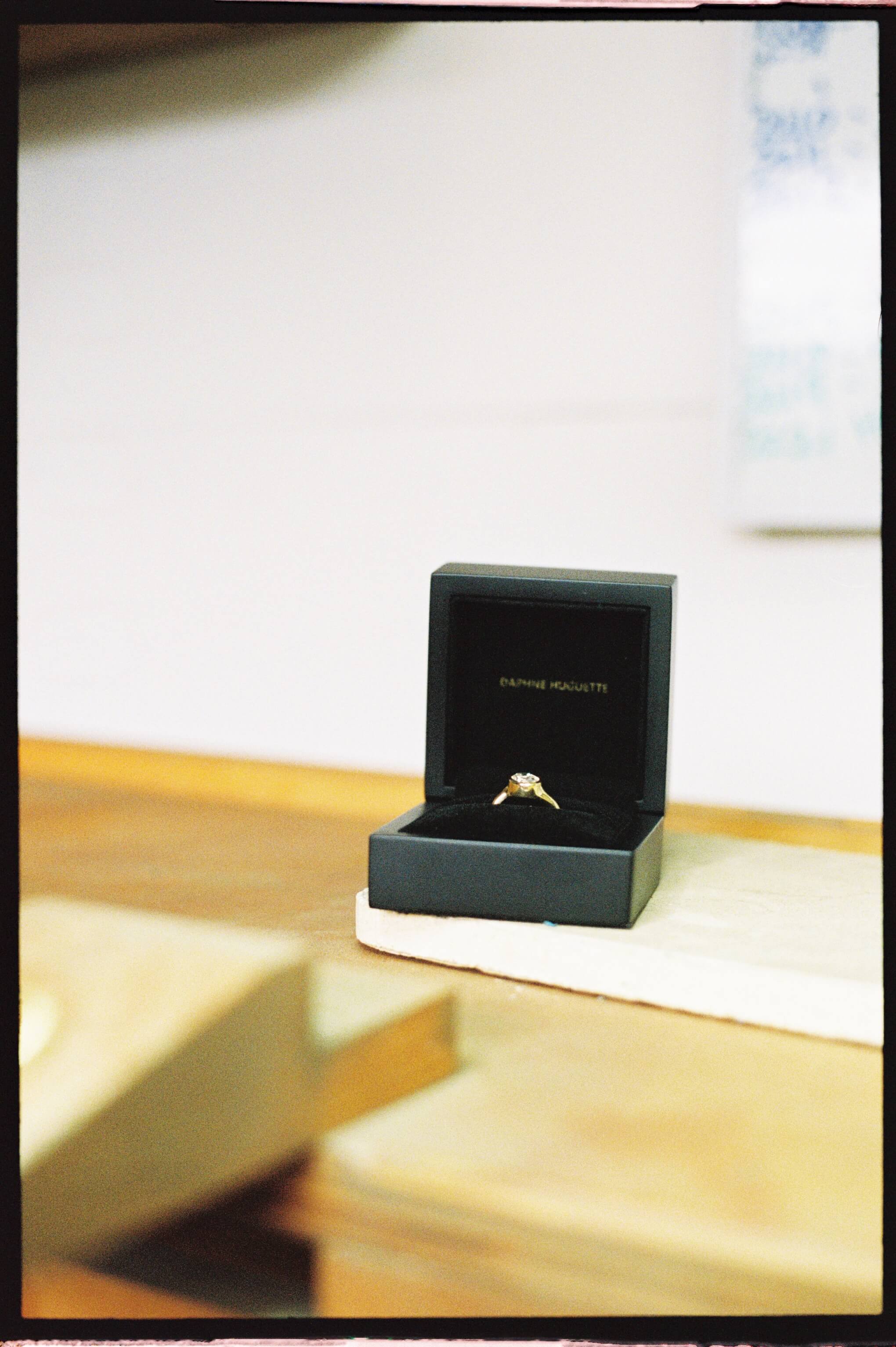 Gold made to order ring in a black box on a wooden surface.