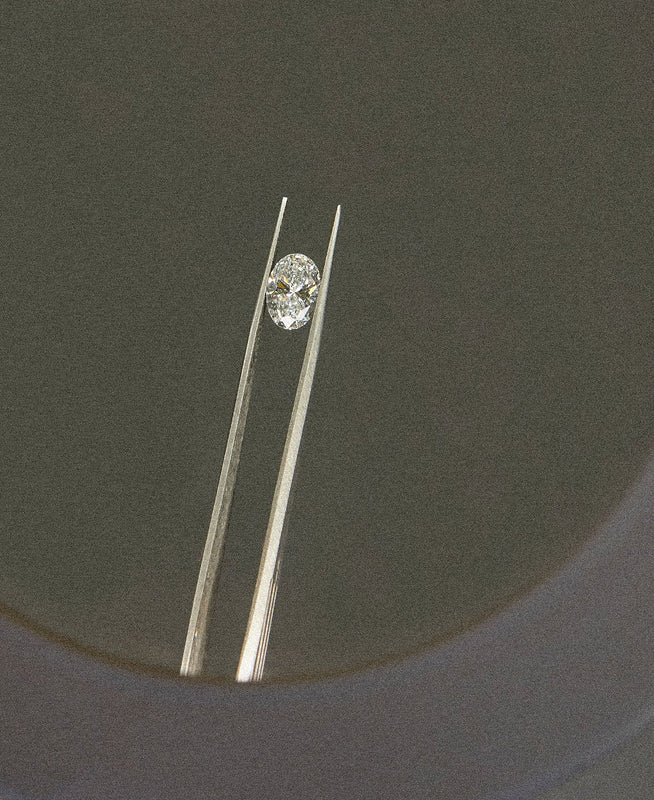 Diamond held between tweezers on a dark background