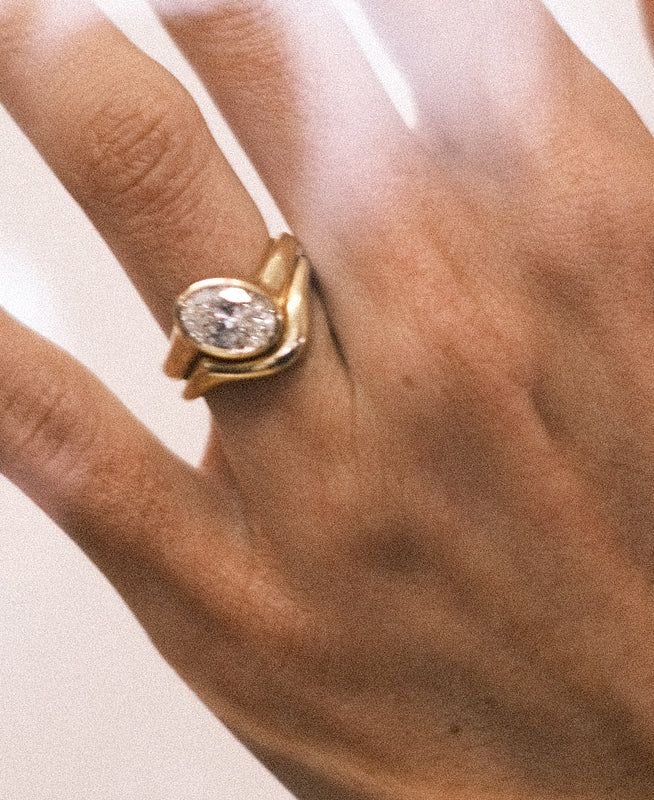 Gold ring with a diamond stacked with a gold band on a person's finger