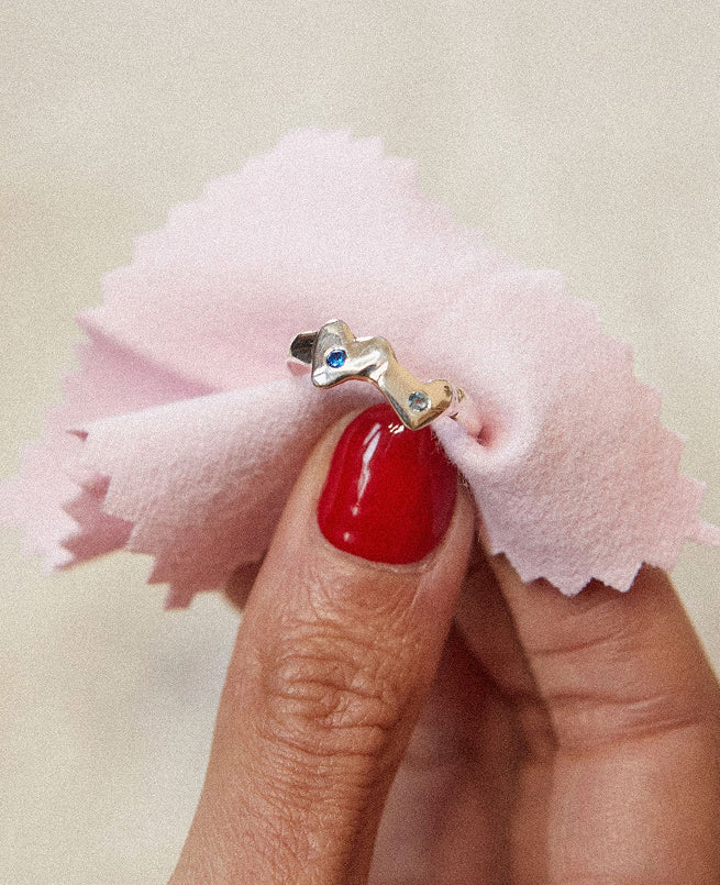 Hand holding Silver ring with gemstones wrapped in pink fabric